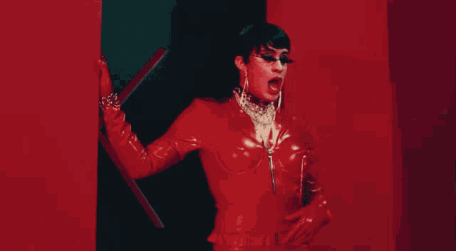 a woman in a red latex outfit is standing in a room