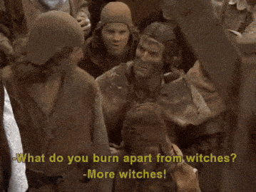 a man in a knight 's armor is talking to a witch who is wearing a horn