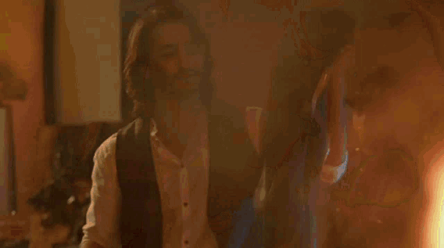 a man in a vest is standing in a dark room