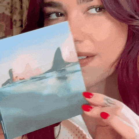 a woman holding a picture of a shark in the ocean