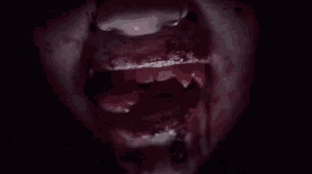 a close up of a person 's mouth with blood and teeth .