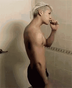 a shirtless young man is brushing his teeth in a bathroom .
