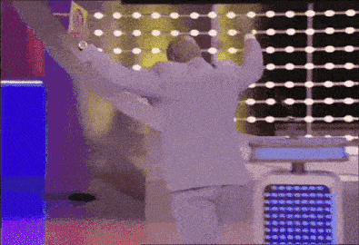 a man in a white suit is dancing on a stage with his arms in the air .