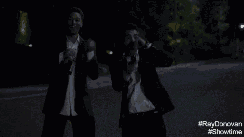 two men in suits are walking down a street at night with #ray donovan #showtime written on the bottom