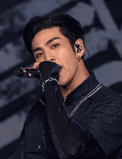 a young man is singing into a microphone while wearing ear buds .