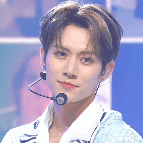 a close up of a young man wearing a microphone and a blue sweater