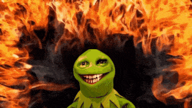 kermit the frog is smiling in front of a large fire