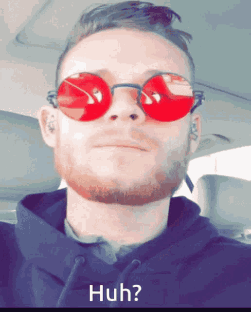 a man wearing red sunglasses and a black hoodie is asking the question huh
