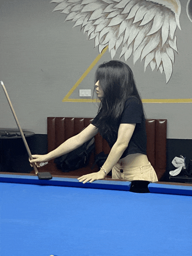 a woman holding a pool cue on a blue pool table