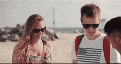 a man and a woman are standing on a beach talking to each other .