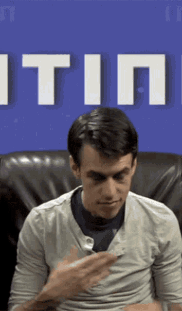 a man is sitting in front of a blue wall that says ' itin ' on it