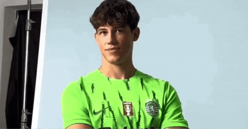 a man in a green shirt giving a thumbs up sign