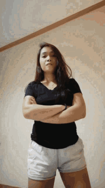 a woman in a black shirt and white shorts with her arms crossed