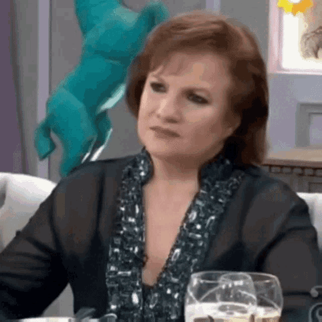 a woman is sitting at a table with glasses of wine and a statue of a horse in the background .