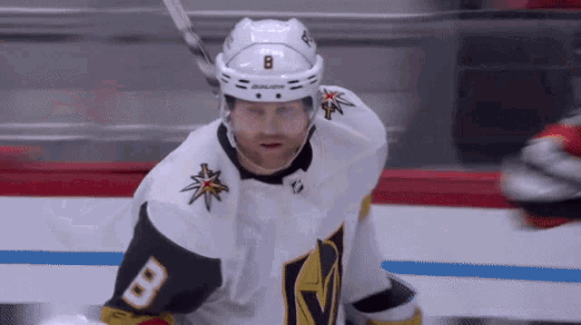 a hockey player wearing a number 8 jersey is standing on the ice .