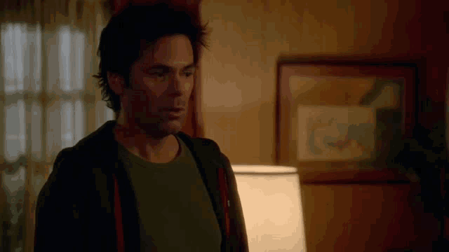 a man is standing in a room with a lamp and a picture on the wall
