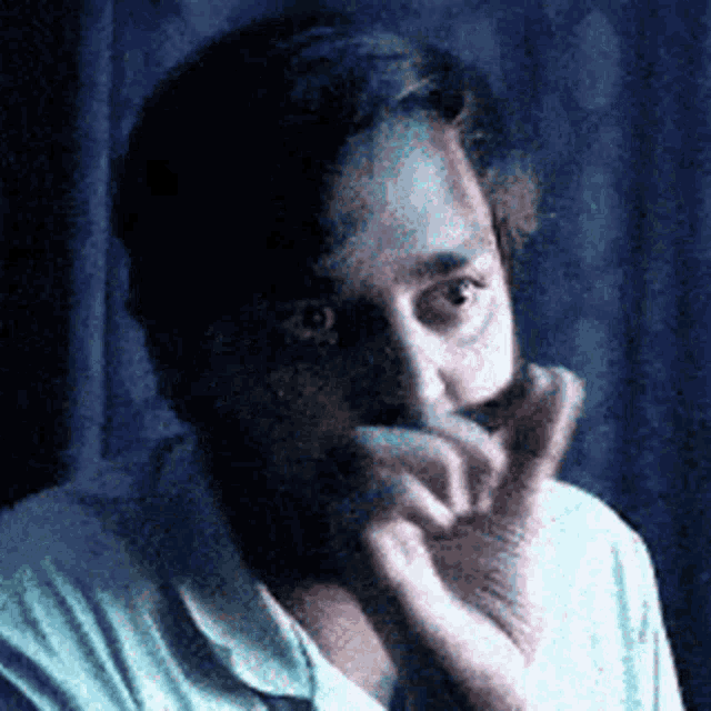 a man is covering his mouth with his hand and looking at the camera