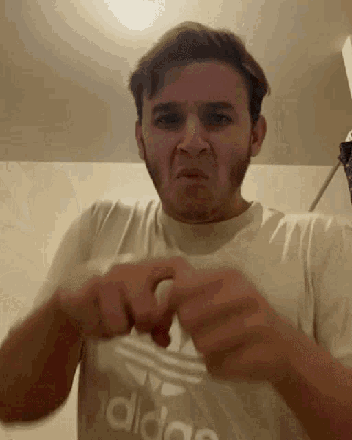 a man wearing an adidas shirt is making a face