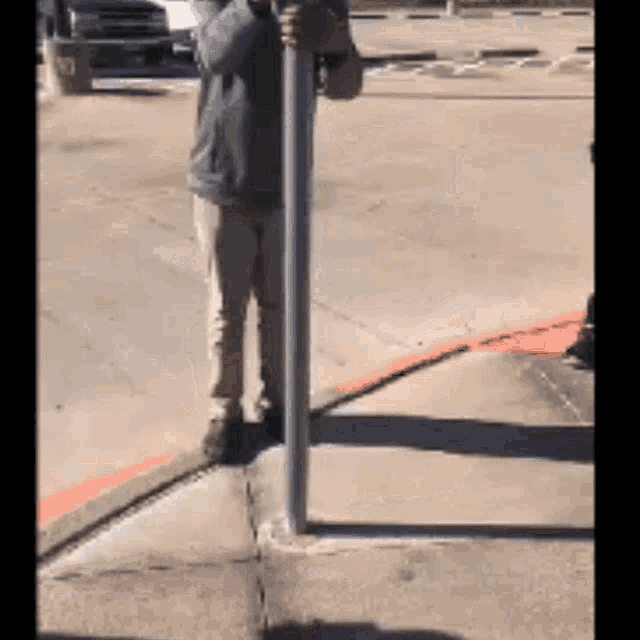 a man is standing on a sidewalk holding onto a pole