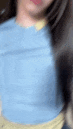 a blurry picture of a woman wearing a blue shirt and a yellow top .
