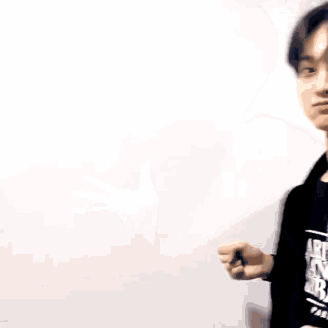 a young man in a black jacket is making a funny face and holding his hands out .