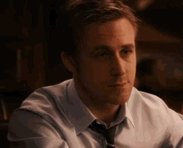 a man in a white shirt and tie is looking down