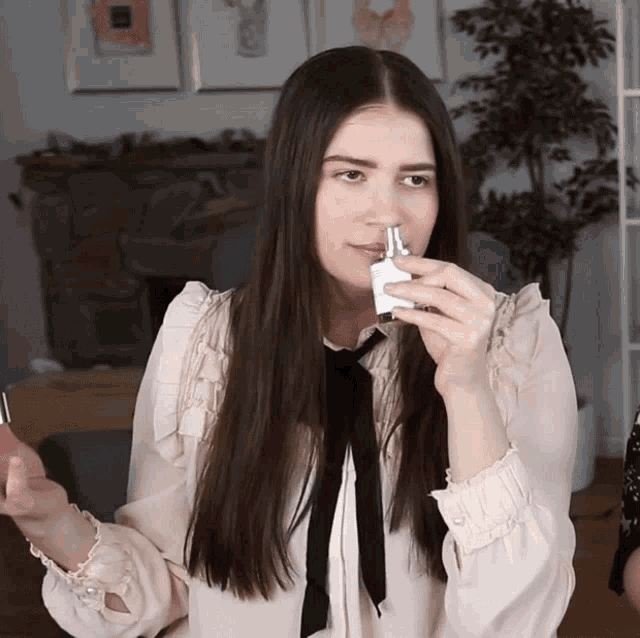 a woman with long hair is holding a small bottle in her hand
