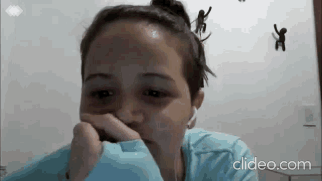 a woman is wearing headphones and covering her mouth with her hand while looking at the camera .
