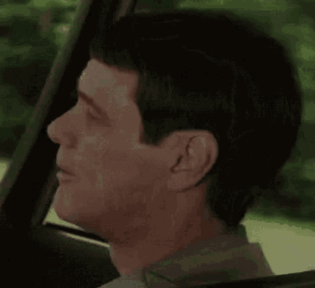 a man is sitting in a car with his mouth open and the word rechazo written on the bottom right corner .