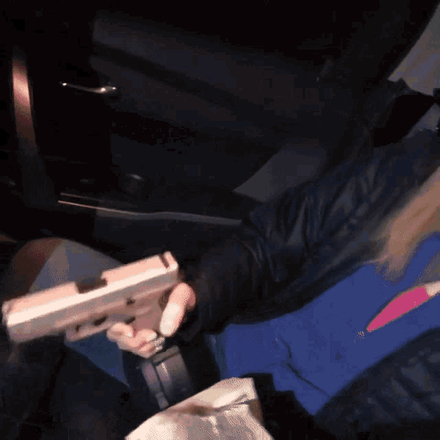 a person holding a gun in their hand in a car