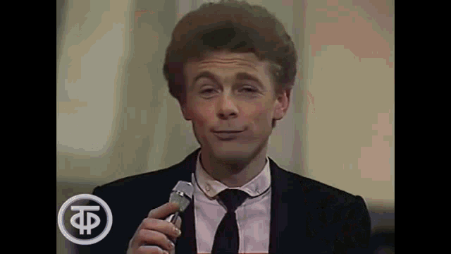 a man in a suit and tie is holding a glass of wine and making a funny face .