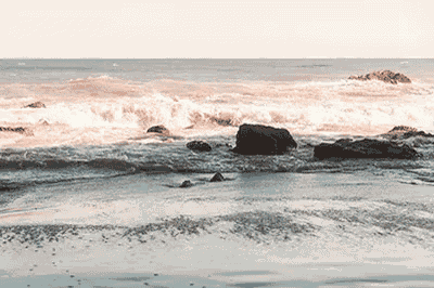 a beach with rocks and waves crashing on the shore