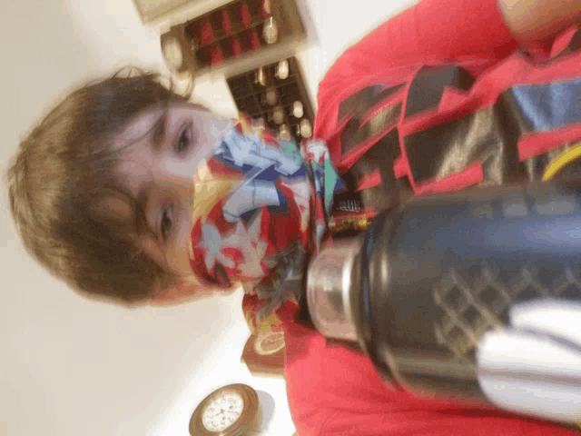 a young boy wearing a red shirt that says ' avengers ' on it