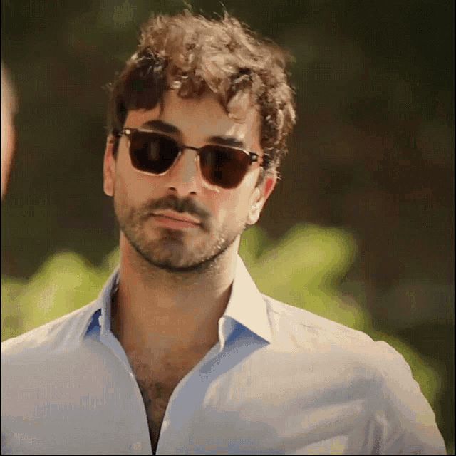 a man wearing sunglasses and a light blue shirt
