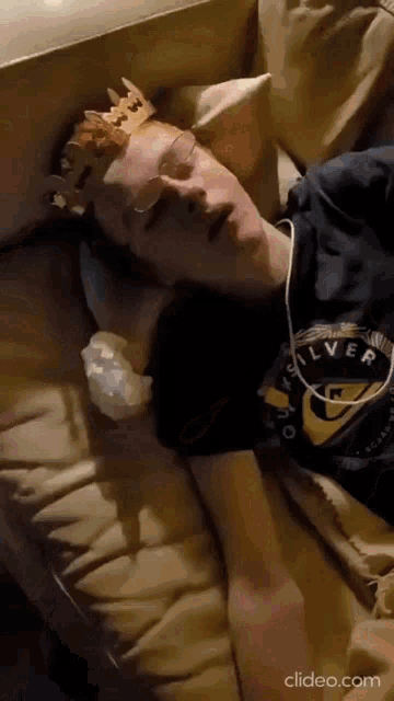 a man wearing a crown and glasses is laying on a couch
