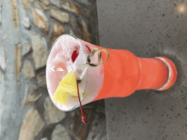 a pink drink with a pineapple slice and a cherry on a toothpick