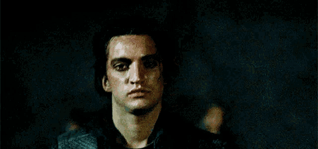 a close up of a man 's face in a dark room with blood on his face .