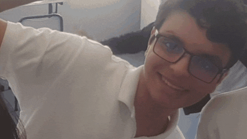 a young man wearing glasses and a white shirt smiles for the camera