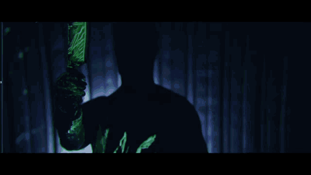 a silhouette of a person holding a knife with a green background