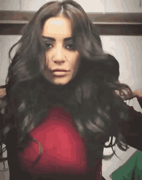 a woman with long dark hair is wearing a red turtleneck sweater