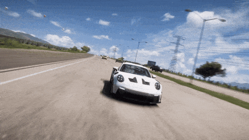 a white car is driving down a road with a blue sky in the background