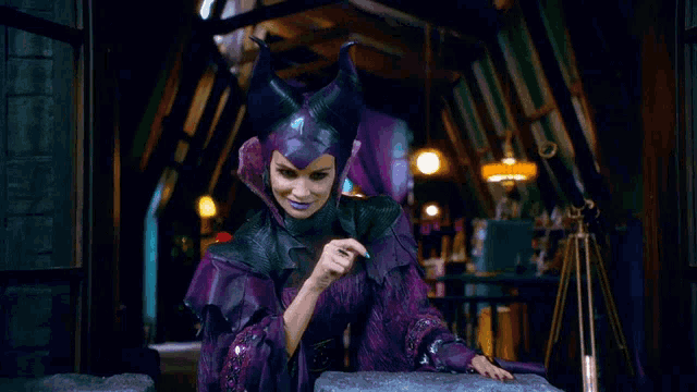 a woman in a purple and black costume with horns is standing in a dark room