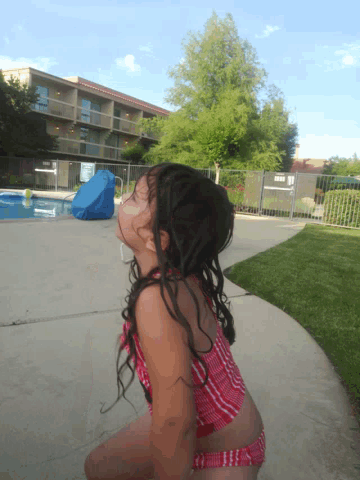 a little girl in a red and white striped bathing suit is standing in front of a pool