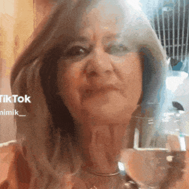 a close up of a woman holding a glass of water with a tiktok logo in the background