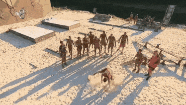 a group of people standing on a sandy beach holding hands .