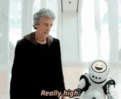 a man is standing next to a robot and saying really high