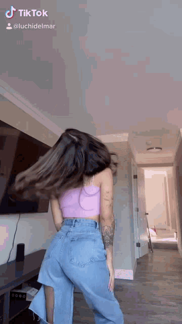 a woman in a purple top and blue jeans is dancing