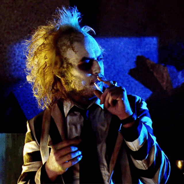 a man in a striped shirt and tie smoking a cigarette