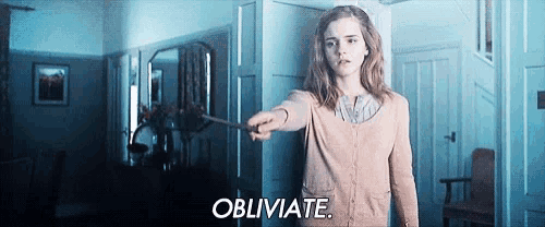a woman is holding a wand in her hand in a room and saying obliviate .