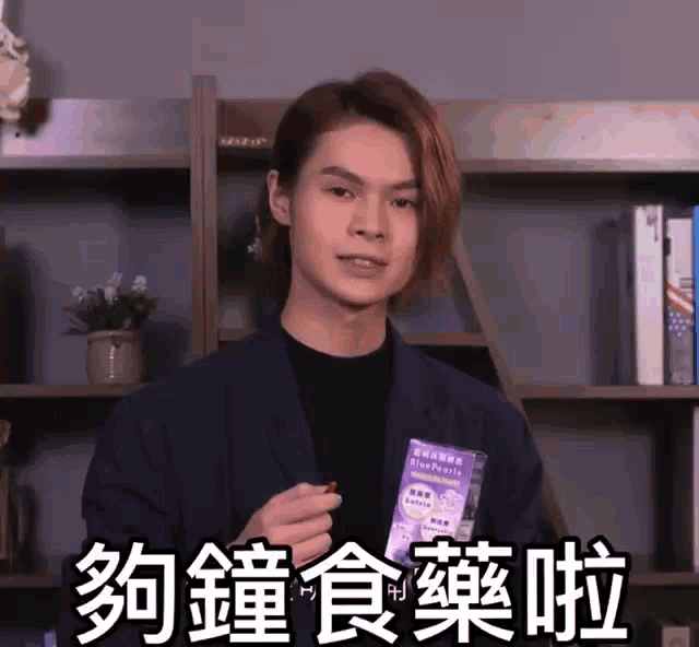 a man in a suit holds a box of blue pearls in his hand
